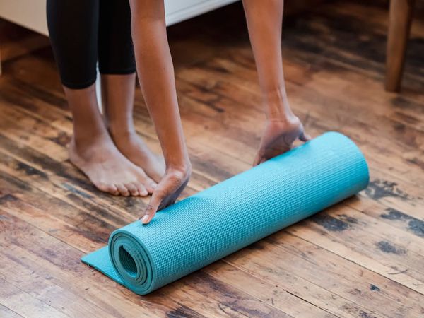 Woman performing a fluid yoga transition on a mat in a bright room.